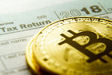 Bitcoins stacked on a 2018 IRS 1040 tax form concept image for cryptocurrency tax issues