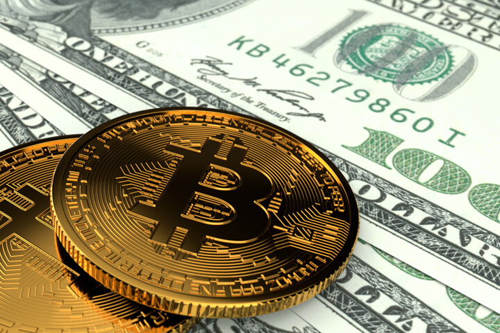 Two Bitcoins laying on U.S. currency