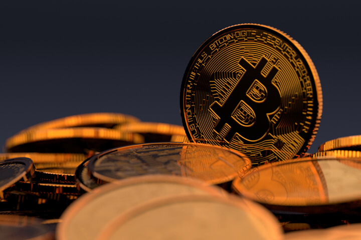 Random pile of Bicoins with one Bitcoin standing vertically