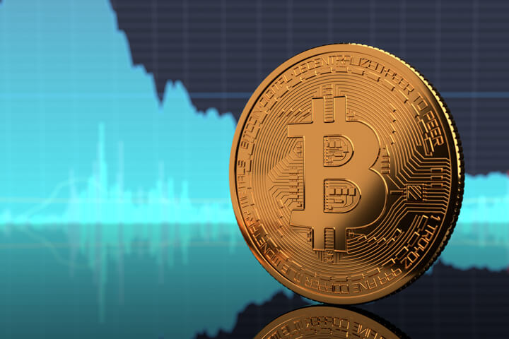 Bitcoin standing on edge on reflective surface with blue BTC stock price area chart in background