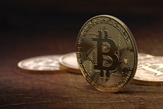 Bitcoin balanced on edge in front of blurred row of other Bitcoins in background