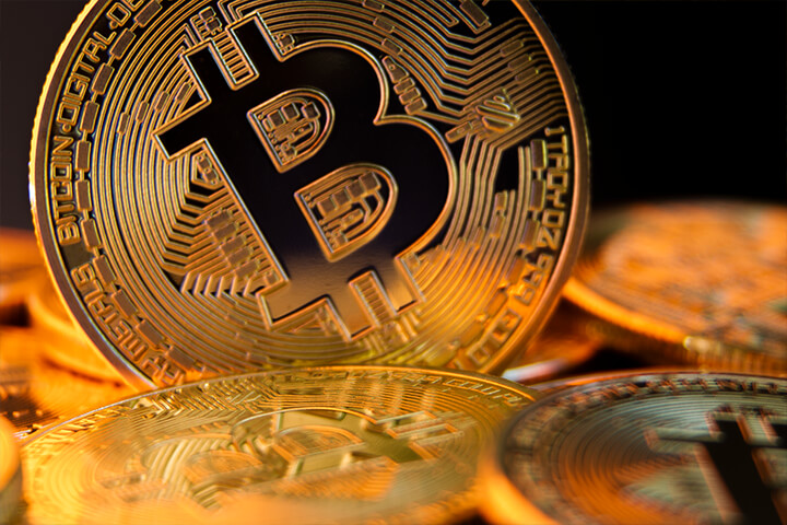 Close view of a bitcoin on edge in a pile of bitcoins