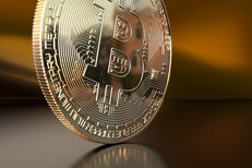 Scratched Bitcoin on edge with orange satin background and reflection
