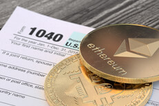 Bitcoin and an Etherum cryptocurrency coins lying on an IRS 1040 tax form concept for cryptocurrency taxes