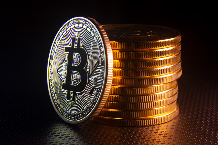 Free photo of a Bitcoin leaning against a stack of Bitcoins dark background