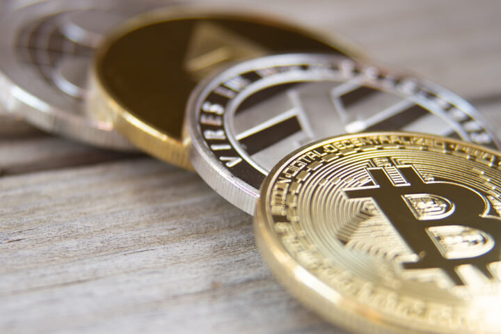 Bitcoin, Litecoin, Ethereum, and Ripple coins on weathered wood planks