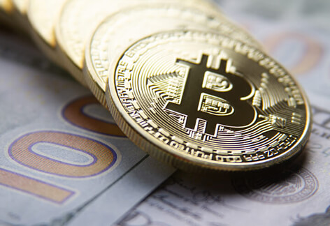 Bitcoins in a row on US 100 dollar bills in background