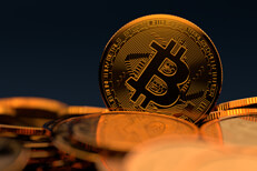 Bitcoin standing on edge in pile of random Bitcoins