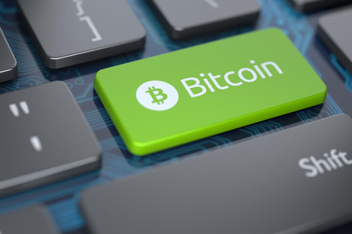 Computer keyboard with green Bitcoin key and circuit board background