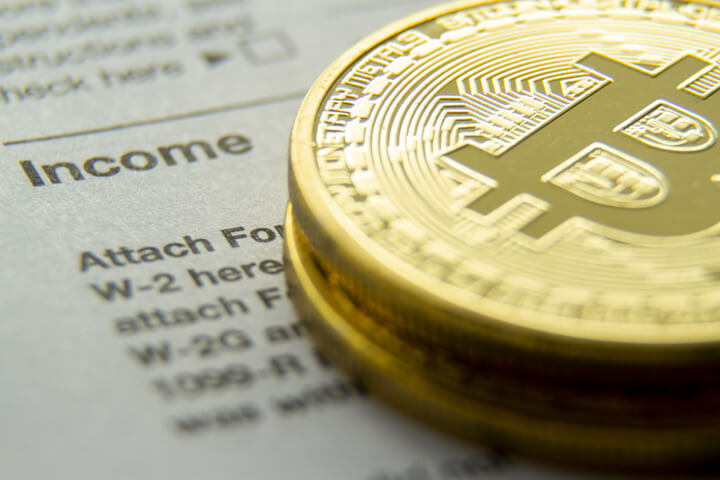 Bitcoins stacked on an IRS 1040 tax form showing the Income information section