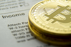 Bitcoins stacked on an IRS 1040 tax form showing the Income information section