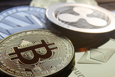 Close up photo of a pile of crypto coins including Bitcoin, Ripple, Litecoin, and Ethereum