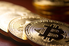 Bitcoins arranged in a row with single coin in background with short depth of field
