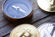 Cryptocurrency coins next to navigation compass