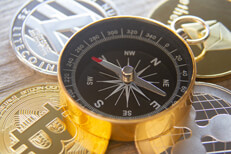 Four cryptocurrency coins with navigational compass on top