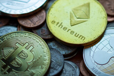 Ethereum, Bitcoin, Litecoin, and Ripple XRP coins with tarnish lying on assorted U.S. currency coins