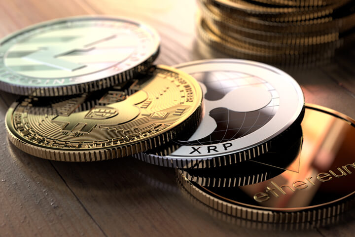 Bitcoin, Ripple, Litecoin, and Ethereum coins in front of stack of Bitcoins