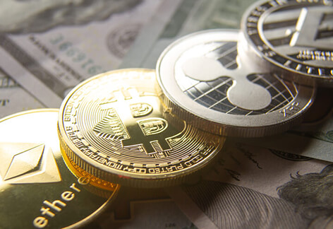 Bitcoin, Ethereum, Litecoin, and Ripple coins in a row on 100 dollar bill background