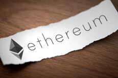 Ethereum cryptocurrency logo printed on torn piece of black scrap paper lying on woodgrain surface
