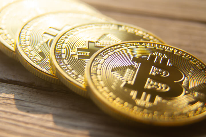 Angled view of four bitcoins in a row on wood planks