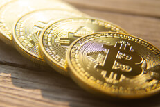 Angled view of four bitcoins in a row on wood planks