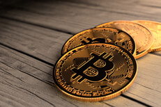 Four Bitcoins in a curved path on weathered wood planks with top right lighting