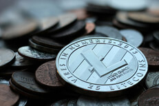 Photo of Litecoin cryptocurrency coin on top of an assorted pile of U.S. currency coins