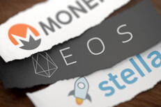 Monero, EOS, and Stellar altcoin cryptocurrency logos printed on torn piece of white scrap paper lying on woodgrain surface