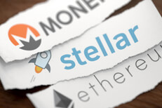 Monero, Stellar, and Ethereum altcoin cryptocurrency logos printed on torn piece of white scrap paper lying on woodgrain surface