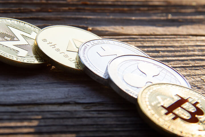 Row of cryptocurrency coins in morning light with hard shadows