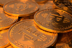 Closer viewpoint of large random pile of Bitcoins illuminated with soft golden light from top and side