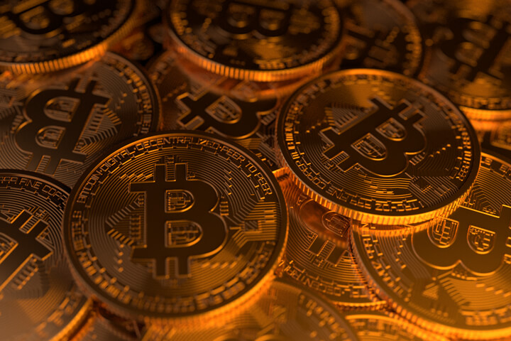 Large random pile of Bitcoins illuminated with soft golden light from side