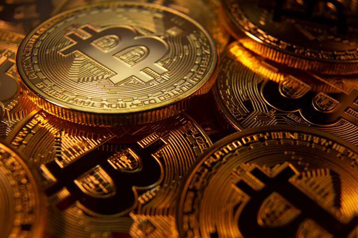 Pile of random Bitcoins in low light with soft spotlight on one coin