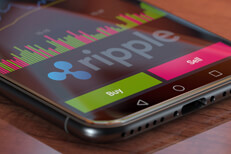 Ripple exchange app on iPhone X screen showing Ripple logo, trading volume, and option to buy or sell cryptocurrency