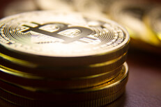 Stack of bitcoins in foreground with row of coins blurred in background