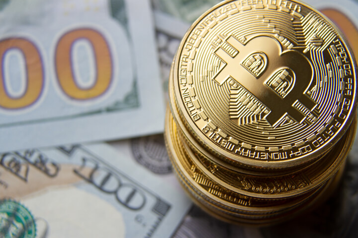 Top view of a stack of bitcoins on 100 dollar bills