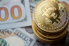 Top view of a stack of bitcoins on 100 dollar bills