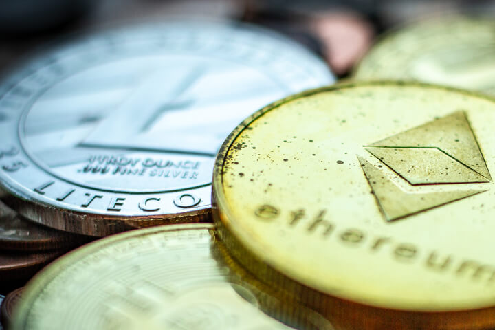 Tarnished Ethereum, Litecoin, Bitcoin, and Monero coins on assorted U.S. currency coins with sharp depth-of-field blur