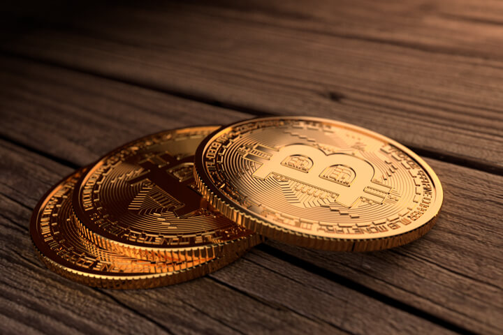 Three Bitcoins stacked in a row on stained wood planks