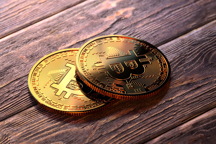 Two Bitcoins on stained wood floor reflecting window light