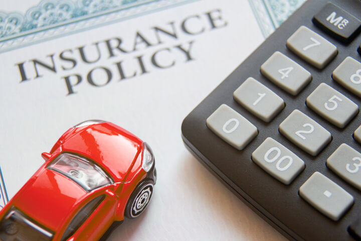 Auto insurance policy with calculator and small red toy car