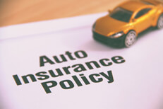 Small yellow car placed on top of an auto insurance policy on a desk