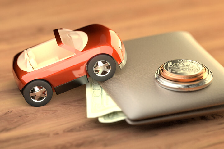 Toy car climbing wallet with small stack of coins on top symbolizing the cost of auto insurance