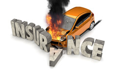 Orange compact car on fire crashed into large stone INSURANCE letters claim concept
