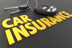 Auto insurance concept image showing car keys and key fob resting on shiny car insurance text