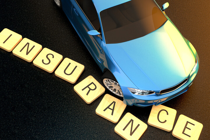Concept image of blue car at sunset skidding through insurance letters on asphalt