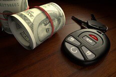 Cost of insurance concept showing two rolls of money next to car keys on desk