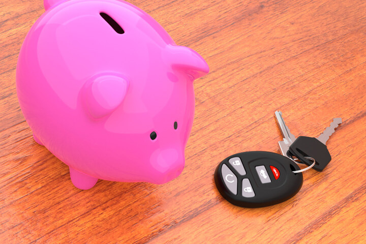 Pink piggy bank on desk next to car keys and key fob