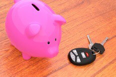 Pink piggy bank on desk next to car keys and key fob