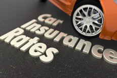 White text car insurance rates on ground in front of orange sports car